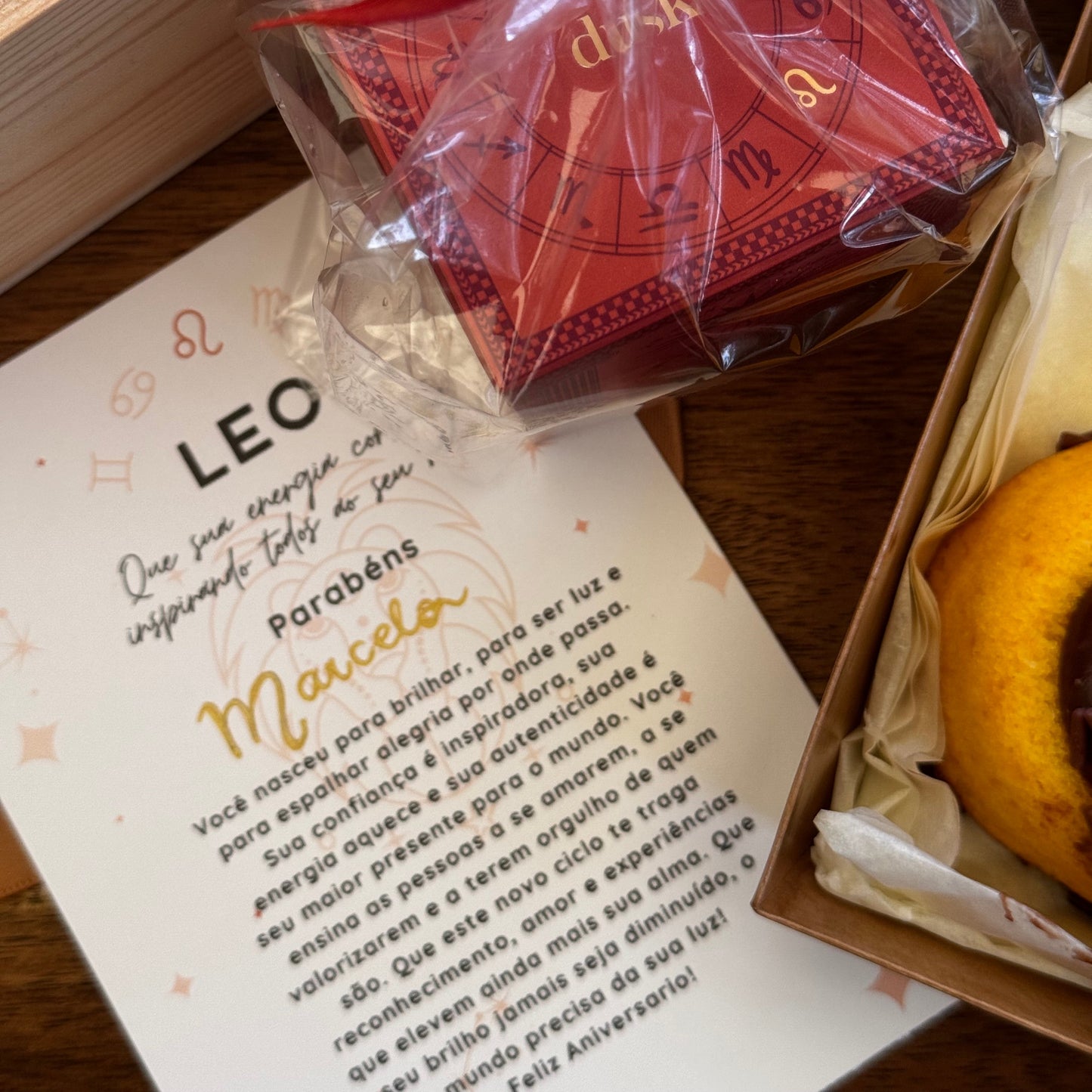Red card with a bow on top of a book with text and astrological symbols.